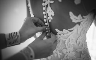 Une demoiselle d'honneur ajuste la robe de la mariée lors de l'essayage