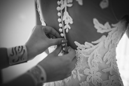 Une demoiselle d'honneur ajuste la robe de la mariée lors de l'essayage
