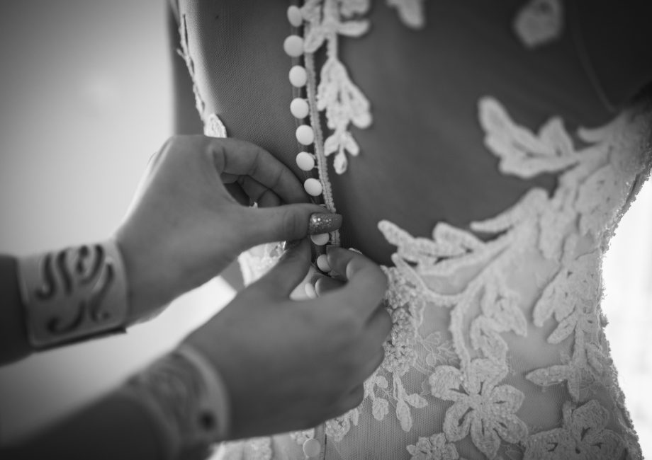 Une demoiselle d'honneur ajuste la robe de la mariée lors de l'essayage