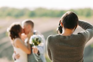 Photographe de mariage photographiant les mariés en pleine nature en automne