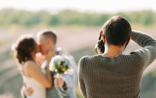 Photographe de mariage photographiant les mariés en pleine nature en automne
